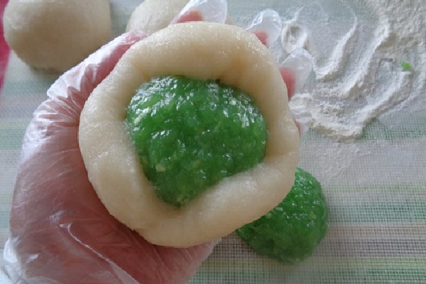 Bột sau khi đã chia, cán dẹp bột, sau đó bỏ phần nhân vào, vo tròn sao cho kín mép bột