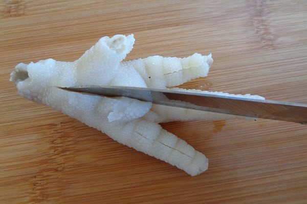 Để rút xương chân gà, bạn đặt chân gà lên thớt, dùng dao khía lên từng ngón chân gà